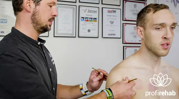 Grzegorz Skorus przeprowadza zabieg klawiterapii w okolicach ramienia pacjenta